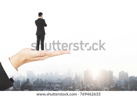 Abstract image of hand holding businessman on city background with copy space and daylight. Research and future concept 