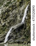 Abstract of mountain waterfall dropping down rocky cliff and into tidewater of Tracy Arm fjord in southeastern Alaska, USA, with digital painting effect