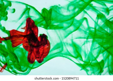 abstract red and green ink patterns dispersing in water with white background