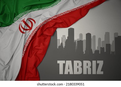 abstract silhouette of the city with text Tabriz near waving colorful national flag of iran on a gray background.3D illustration