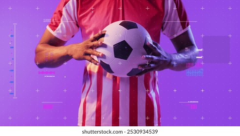 African American man holds a soccer ball, with copy space. Studio shot with a vibrant purple background emphasizes the sporty theme. - Powered by Shutterstock