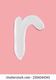 Alphabet Letter R Handwritten, White Cream Moisturiser Texture Smear Stroke Isolated On Pink Background
