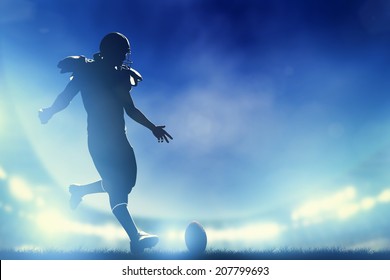 American football player kicking the ball, kickoff. Night stadium lights