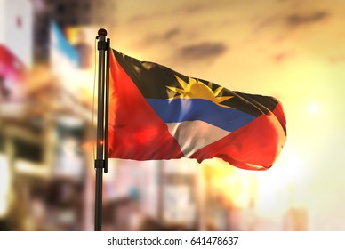 Antigua and Barbuda Flag Against City Blurred Background At Sunrise Backlight 3D Rendering