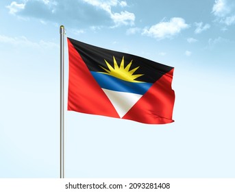 Antigua and Barbuda flag waving on blue sky background with clouds. Close up waving flag of Antigua and Barbuda. Antigua and Barbuda flag waving in the wind.