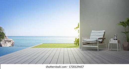 Armchair on terrace near swimming pool and garden in modern beach house or luxury villa. Wooden deck 3d rendering with sea view.
