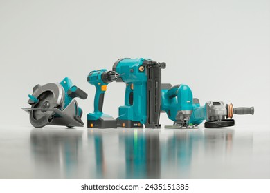 An array of essential cordless power tools, featuring a drill, circular saw, and nail gun, meticulously arranged on a reflective white backdrop, perfect for professional construction and DIY projects.
