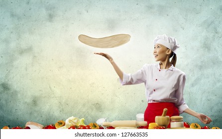 Asian Female Cook Making Pizza Standing Against Color Background