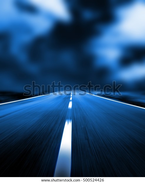 Asphalt\
track at high speed in bad weather. Dashed dividing line on road.\
Rainy sky, storm clouds. Dark blue\
background.