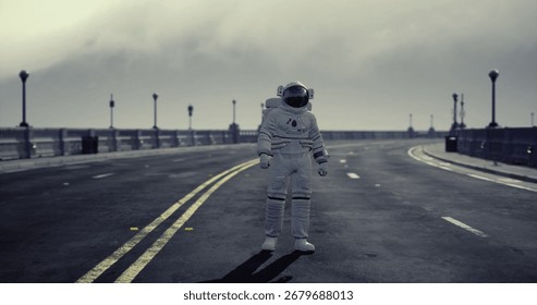 An astronaut stands alone on an empty road with faded yellow lines, surrounded by a moody sky and distant structures, creating an unusual contrast between space and urban setting.