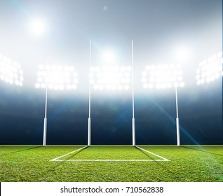 An Aussie Rules Football Stadium With A Marked Green Grass Pitch And Goal Posts In The Nighttime Under Illuminated Floodlights - 3D Render