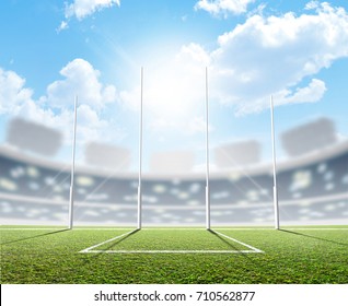 An Aussie Rules Football Stadium With A Marked Green Grass Pitch And Goal Posts In The Daytime Under A Blue Sky - 3D Render