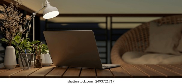 Back view image of a laptop computer on a wooden desk on a balcony at dusk, illuminated by a table lamp on the table. outdoors workspace. 3d render, 3d illustration