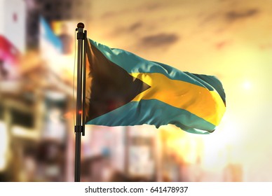 The Bahamas Flag Against City Blurred Background At Sunrise Backlight 3D Rendering