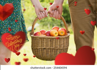 Basket of apples being carried by a young couple against happy valentines day - Powered by Shutterstock