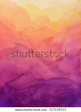 Beautiful hues of yellow gold pink and purple in hand painted watercolor background design with paint bleed and fringing in colorful sunrise or sunset colors in abstract cloudy mountain shapes.