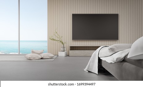 Bed On Concrete Floor Of Bright Bedroom Against TV In Modern Beach House Or Luxury Hotel. Minimal Home Interior 3d Rendering With Sea View.