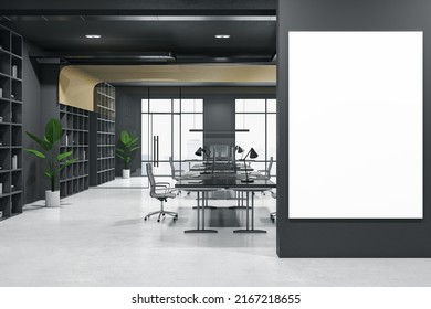 Big Blank White Poster With Space For Your Logo Or Text On Black Wall In Dark Interior Office With Black Walls, Workspaces With Modern Computers On Concrete Floor And Green Plants. 3D Rendering Mockup