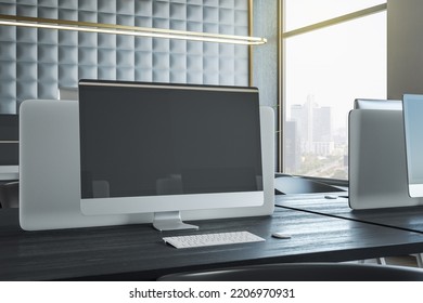 Black Blank Modern Computer Monitor Screen With Place For Your Logo Or Text On Dark Wooden Table In Sunlit Coworking Office With City View And Golden Lamps Above Workspaces. 3D Rendering, Mock Up