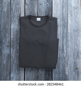 Black Folded  T-shirt On Wooden Background