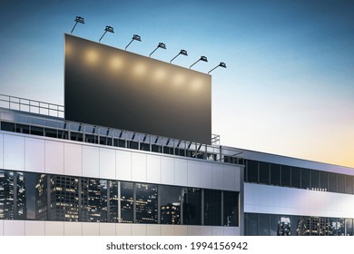 Black Lighted Billboard With Copyspace On Business Center Rooftop With Spotlights And Night City Skyscrapers Reflection In Building Windows. 3D Rendering, Mockup