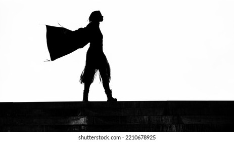 Black Silhouette Of Female Superhero Silhouette With Cape In Action Poses. Windy Weather. Isolated On White  Sky Background. Photo Of Female Super Hero. Woman Walking Against The Wind. Illustration.