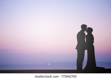 black silhouette of lover couple hug and kiss in wedding event on the beach at sunset time hour background,love concept - Powered by Shutterstock