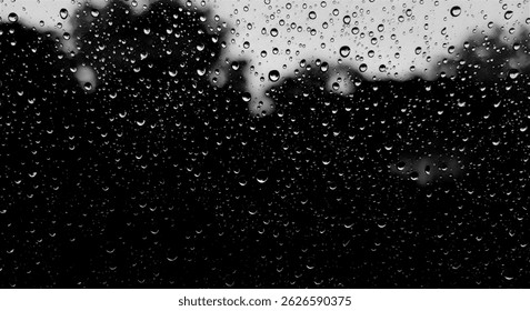 Foto en blanco y negro de gotas de lluvia en una ventana de vidrio, fondo borroso con gotas de agua creando una textura dramática y malhumorada.