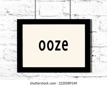 Black Wooden Frame With Inscription Ooze Hanging On White Brick Wall 