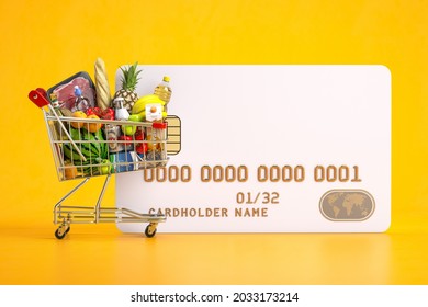 Blank credit card and shopping cart full of grocery products . Online food ordering and delivery service concept. 3d illustration