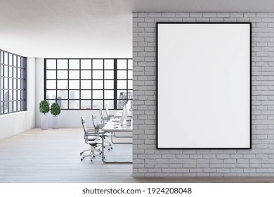 Blank White Poster In Black Frame On Light Brick Wall In Spacious Modern Office With Wooden Floor And Big Window. Mock Up. 3D Rendering