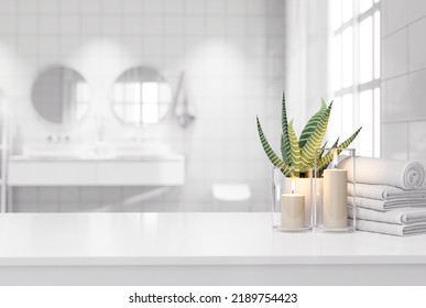 Blank White Table Top For Copy Space 3d Render Decorated With Glass Candle Holders With Flames. Cotton Towel And A Potted Plant With A Blurry Bathroom Background.