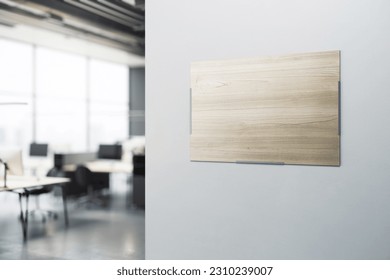 Blank wooden printed poster with place for your logo or text on light grey wall background in modern office area with blurred furniture on background. 3D rendering, mockup