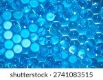 Blue hydrogel beads in two layers: the chaotic top layer is in focus, the bottom layer, arranged in ordered hexagons, is blurred. An abstract background, texture resembling an alien material, cells.
