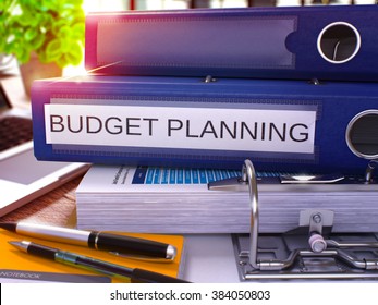 Blue Ring Binder With Inscription Budget Planning On Background Of Working Table With Office Supplies And Laptop. Budget Planning Business Concept On Blurred Background. 3D Render.