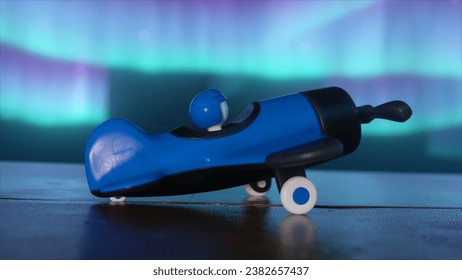 A blue toy airplane for boys with a pilot inside on a wooden table. The cosmic environment and the northern lights. The concept of aviation. 3D illustration - Powered by Shutterstock