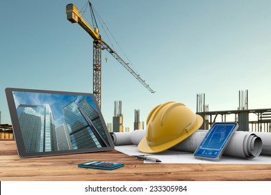 blueprints, safety helmet and computer in construction site - Powered by Shutterstock