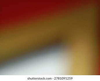 A blurred abstract background featuring a gradient of warm colors, transitioning from deep red to golden yellow with a streak of white and grey.