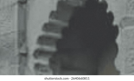 A blurry grayscale image shows what appears to be a damaged or dilapidated building structure. The details are indistinct due to the poor image quality.