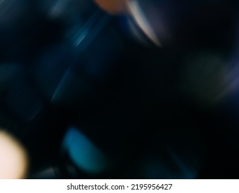 Bokeh light overlay. Lens flare texture. Blur glare reflection. Defocused purple blue orange color glow flecks on dark night black abstract copy space background.