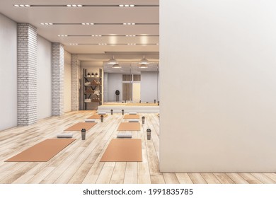 Bright concrete yoga gym interior with equipment, blank mockup space on wall, daylight and wooden flooring. Healthy lifestyle concept. Mock up, 3D Rendering