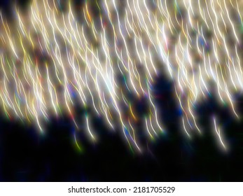 Bright Light Trails Of Embers Of A Fireworks Burst Falling Toward Earth At A Holiday Celebration At Night. Long Exposure With Motion Blur. Light Painting, With Digital Glow Effect.