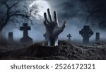 Buried human hand rising out of ground in misty graveyard cemetery