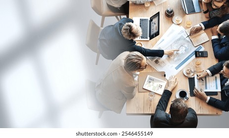 Business meeting with diverse professionals around a table, discussing documents and laptops. Teamwork and collaboration in a corporate setting. Business teamwork concept with copy space. - Powered by Shutterstock