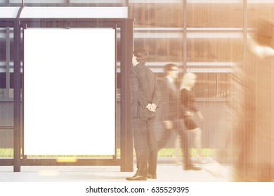 Business People Are Passing By A Bus Stop With A Blank Vertical Poster Standing In A Street Near An Office Building. 3d Rendering, Mock Up, Toned Image