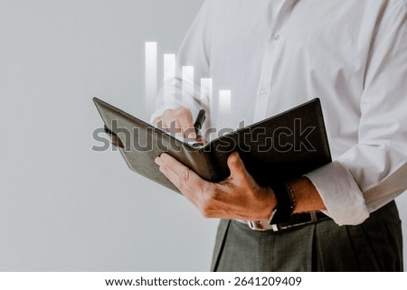 Businessman holding a notebook, analyzing data. Male professional in formal attire, reviewing charts. Business, data analysis, and notebook in focus. Business success image.