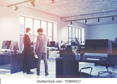 Businessmen in a white open space office corner with a concrete floor, two large windows and black wooden desks with computers on them. 3d rendering toned image - Shutterstock ID 753849217