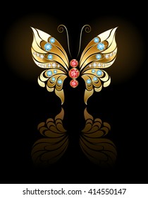 Butterfly jewelry made of gold, adorned with precious round gems on dark background.