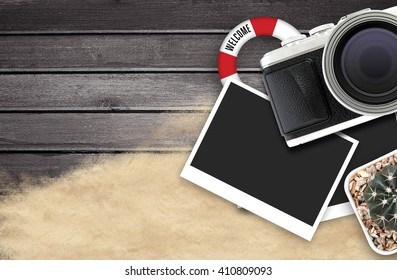 camera and blank photo frames on black wooden table. top view, travel concept 