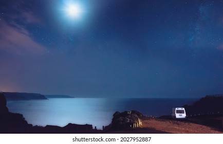 Camper Van Parked On A Cliff Under The Night Sky And Stars And Overlooking The Ocean 